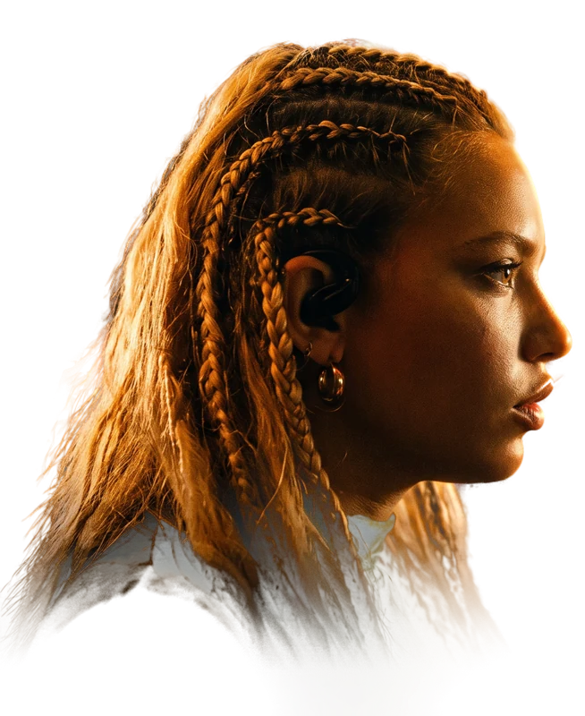 Ro-AN, in profile, braids, an earpiece in her ear, lit in amber.